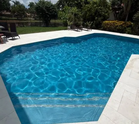 Sparkling blue pool with balanced water chemistry and a travertine deck at a Fort Pierce home