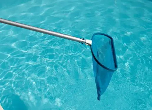 Leaf skimmer net removing debris from turquoise water during a one-time cleaning by Fort Pierce Pool Maintenance