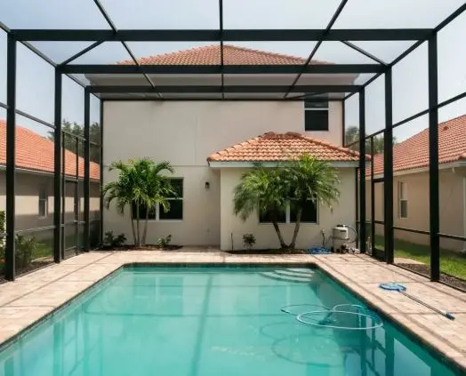 Screened pool enclosure behind a tile-roof home with palm trees and a clean pool in Fort Pierce