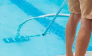 Close-up of a pool vacuum head on a pole cleaning the pool floor