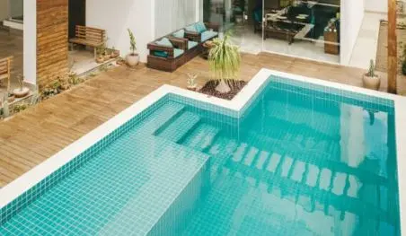 Tiled turquoise pool with built-in steps and a wood deck at a Fort Pierce home cared for by Fort Pierce Pool Maintenance
