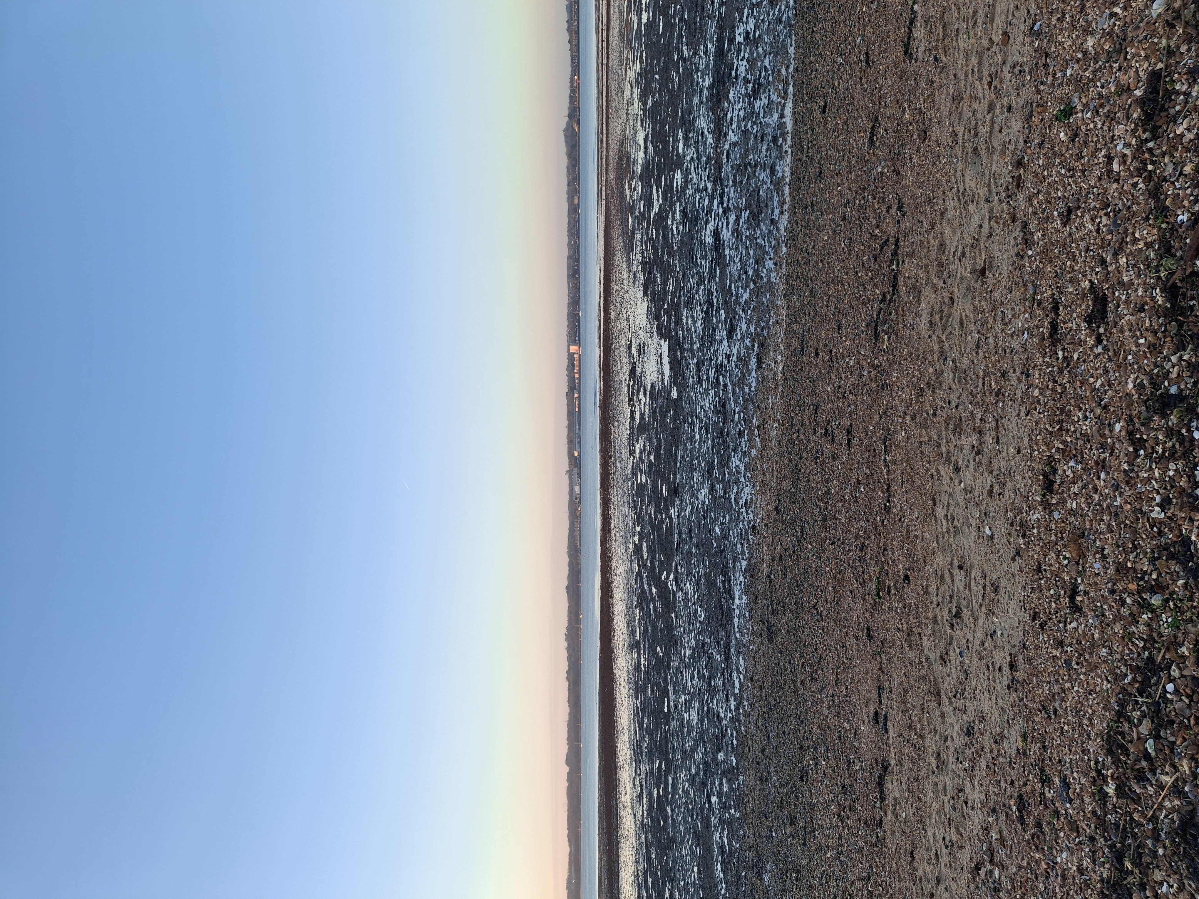 beach waves blue sky with pink hue on horizon
