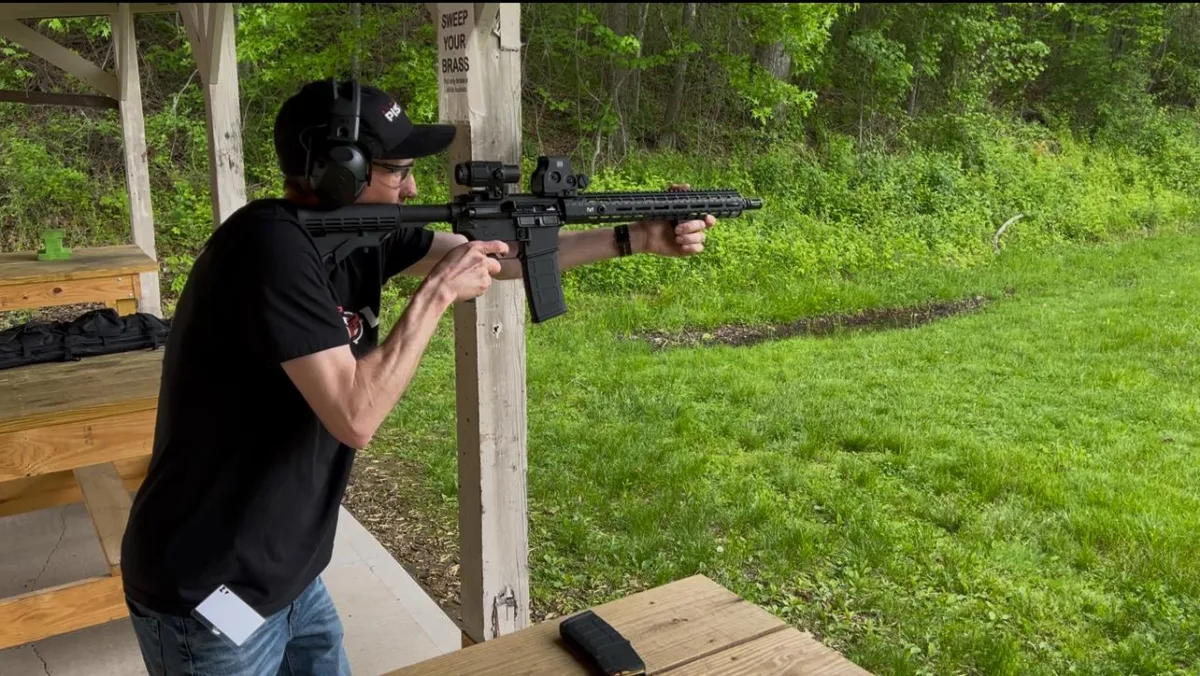 A firearms instructor firing a rifle at a high end outdoor gun club.