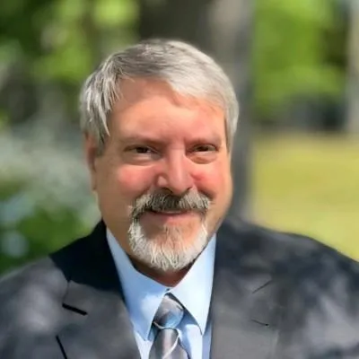 A smiling woman in her 40s, standing in a cozy kitchen, holding a glass of water and a LumiVitae bottle, sunlight streaming through the window, expressing renewed energy and joy.