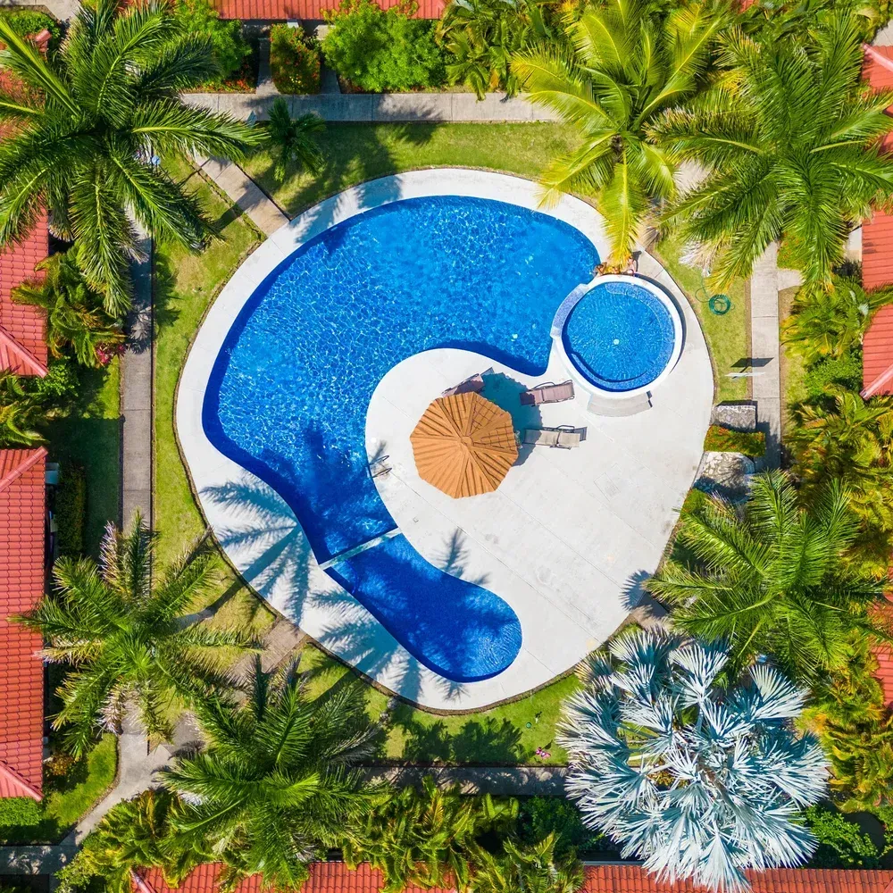 A young couple stands in front of a newly purchased beach home, holding a 'Sold' sign.