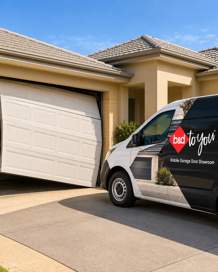 a sectional garage door that is out of its tracks and sitting on an angle with a B&D repair van in the driveway 