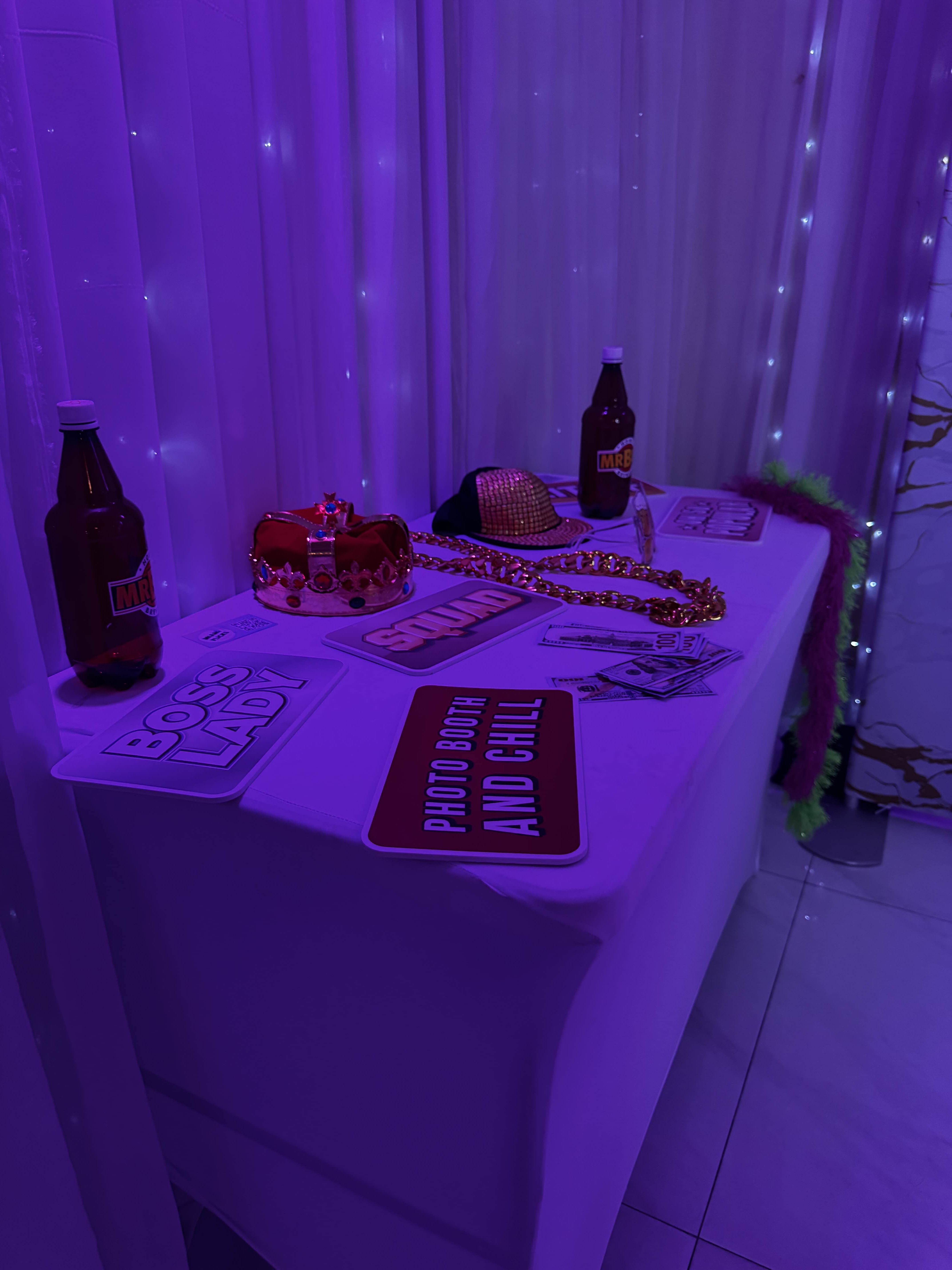 Corporate professionals in business attire posing with branded props in a sleek photo booth at a Miami conference, modern decor, and lively networking vibe.