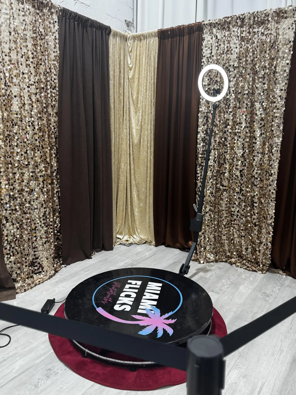 Corporate activation with the Orbit360 Booth, branded step-and-repeat, neon blue uplighting, smiling attendees.