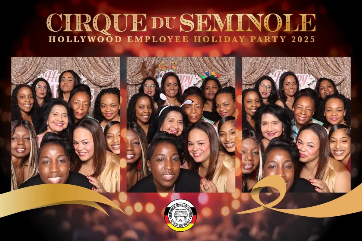 Corporate professionals in business attire posing with branded props in a sleek photo booth at a Miami conference, modern decor, and lively networking vibe.