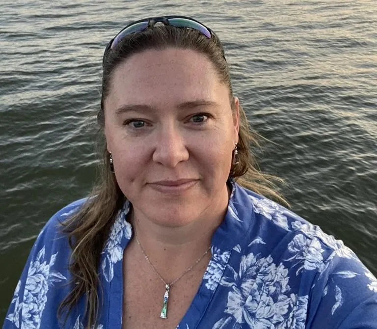 headshot of the author with a lake behind her