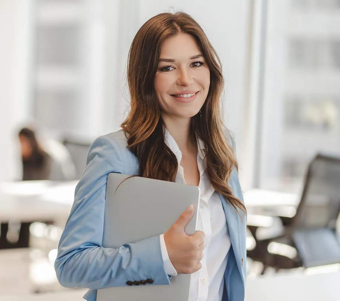 a professional woman holding a laptop and smiling