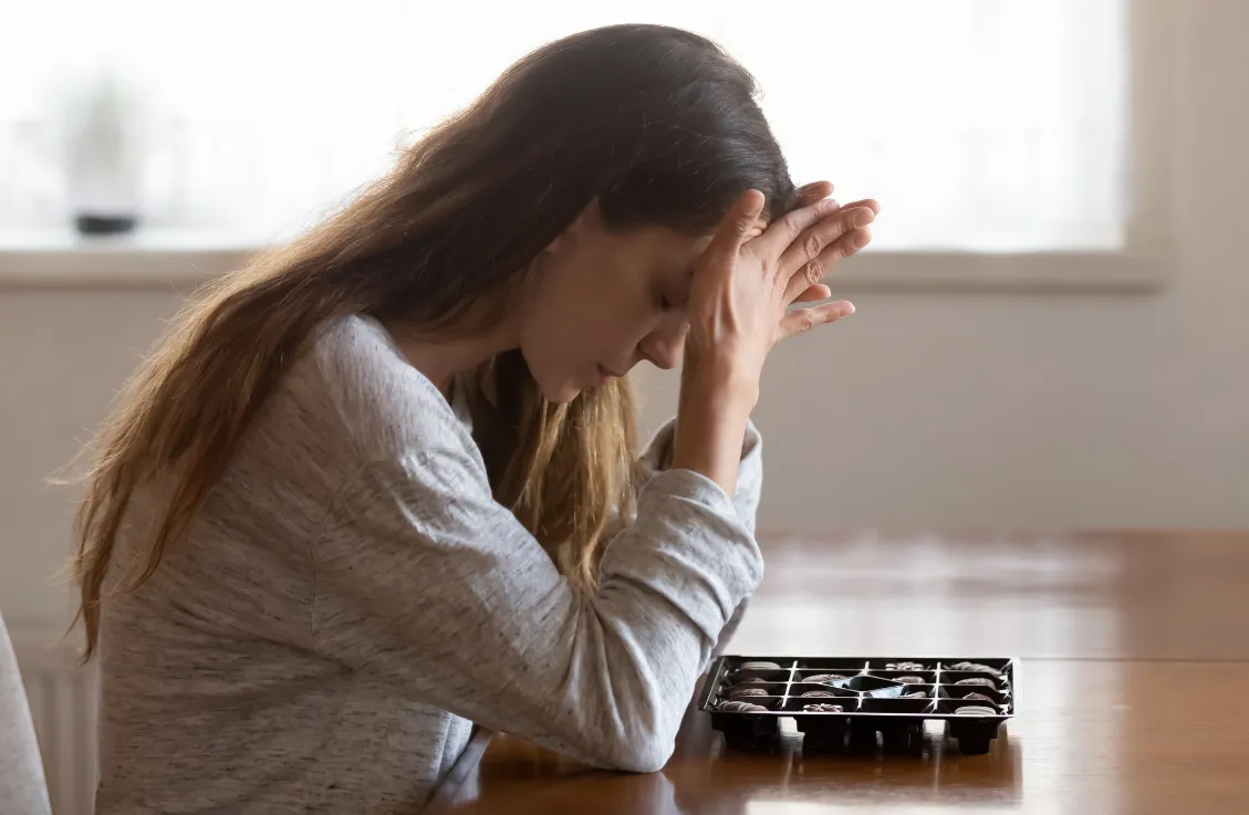 woman sitting at table with chocolate feeling guilty