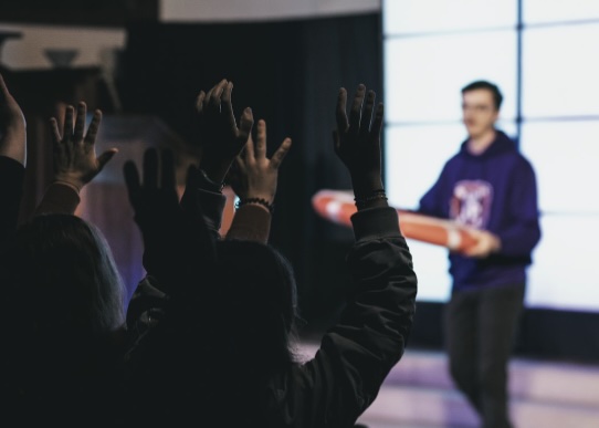 People raising hands towards a man holding a skateboard
