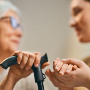older woman and audiologist holding hands
