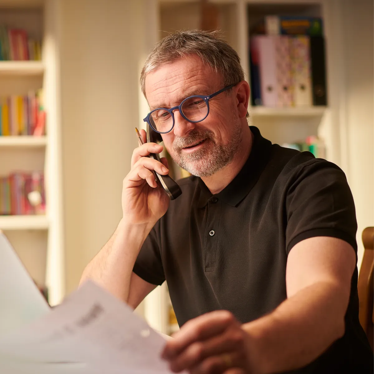Man on his phone holding a  paper
