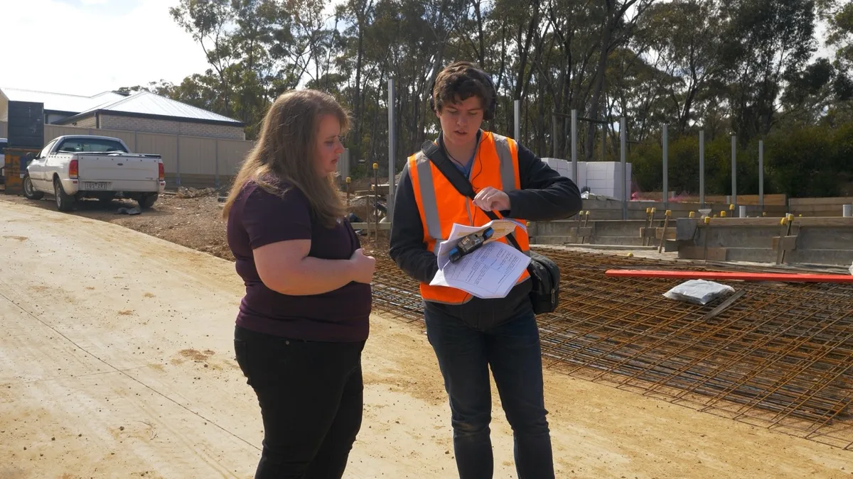 Presenter speaking with a worker in a high visibility vest on a building site