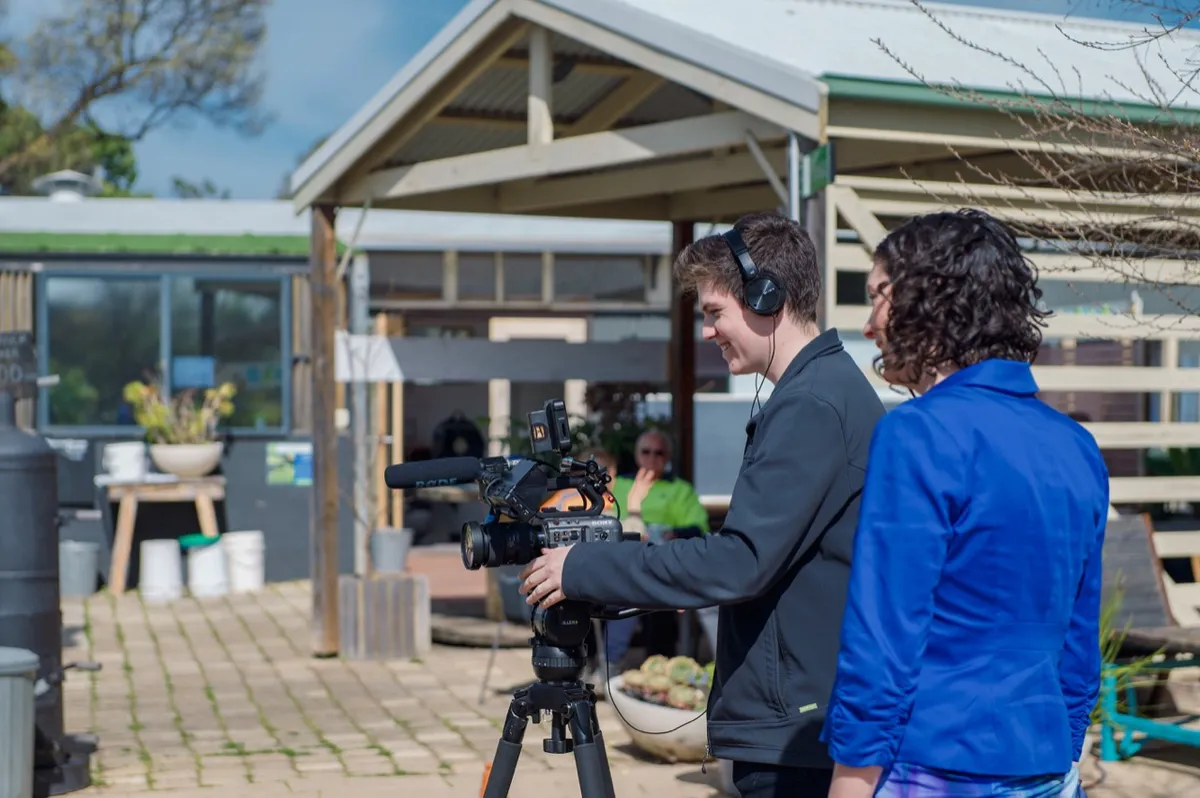 Camera operator filming an interview beside the nursery pavilion