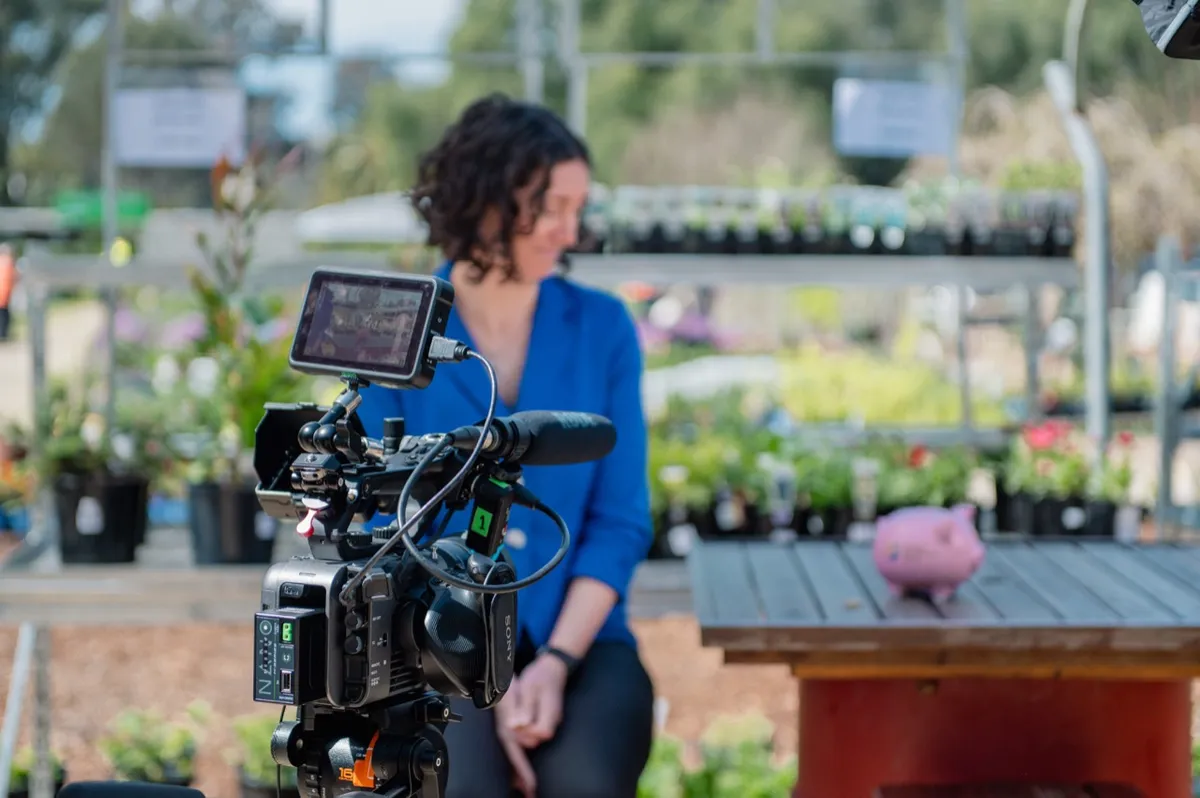 Camera monitor framing an interview with a woman in blue at a plant nursery