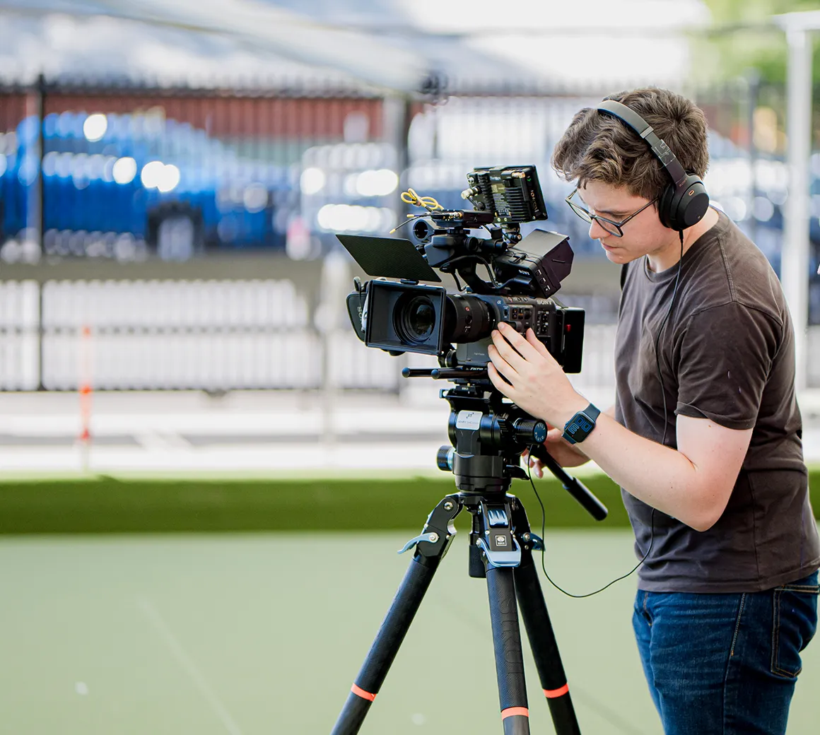 Henry Sheahan operating a cinema camera on a tripod at an outdoor shoot