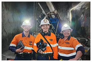 Three miners in hi-vis and hard hats with Henry underground