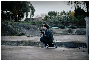 Henry crouched with a gimbal on a concrete embankment