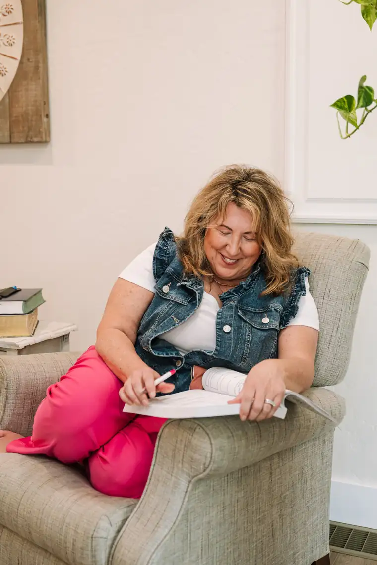 Woman in a denim vest writing in her journal