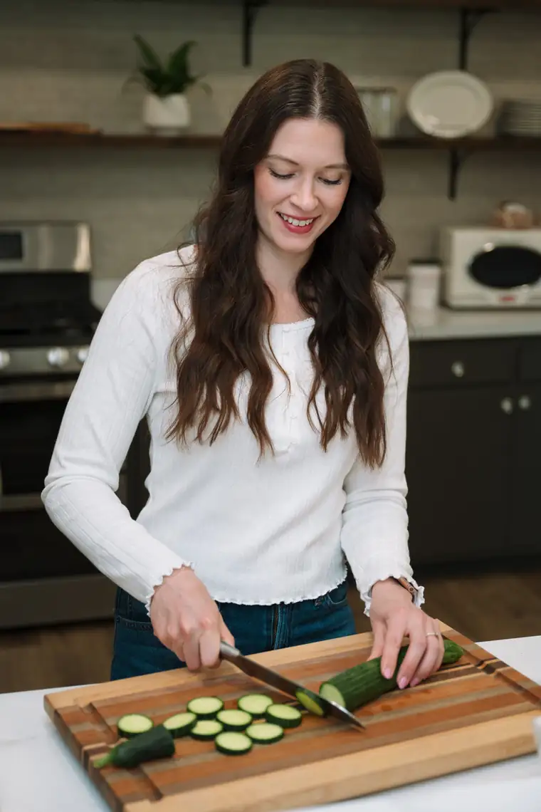 Woman slicing a cucumber in her kitchen