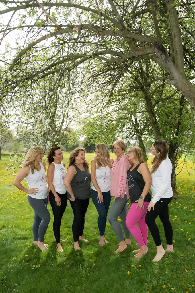 Seven Certified Fast to Faith Coaches standing together under a flowering tree