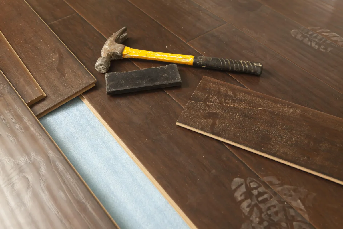 a hammer and a tile on a wood floor