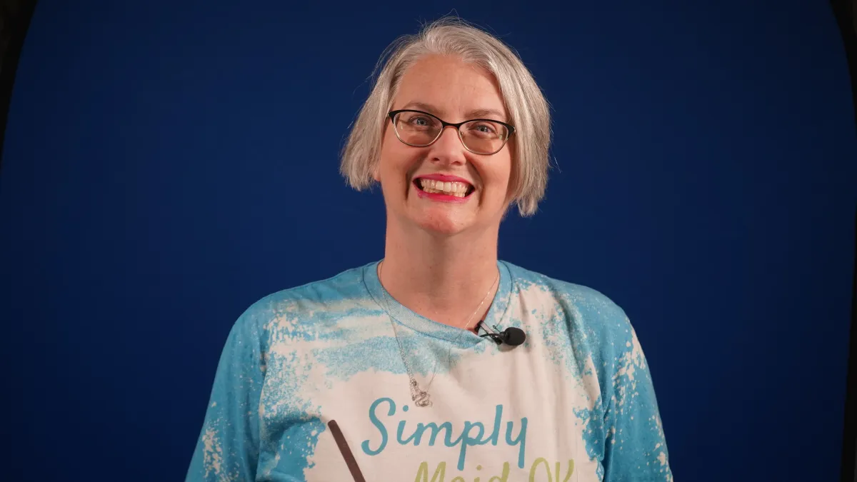 Stephanie Ramsey, smiling and wearing a "Simply Maid" shirt, promoting her cleaning service against a blue background.