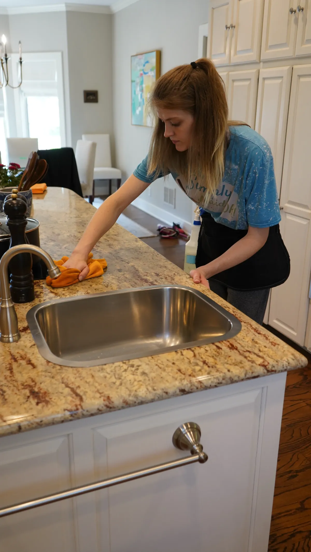 Woman cleaning kitchen countertop with orange cloth, showcasing Simply Maid's commitment to reliable home cleaning services in Collinsville.