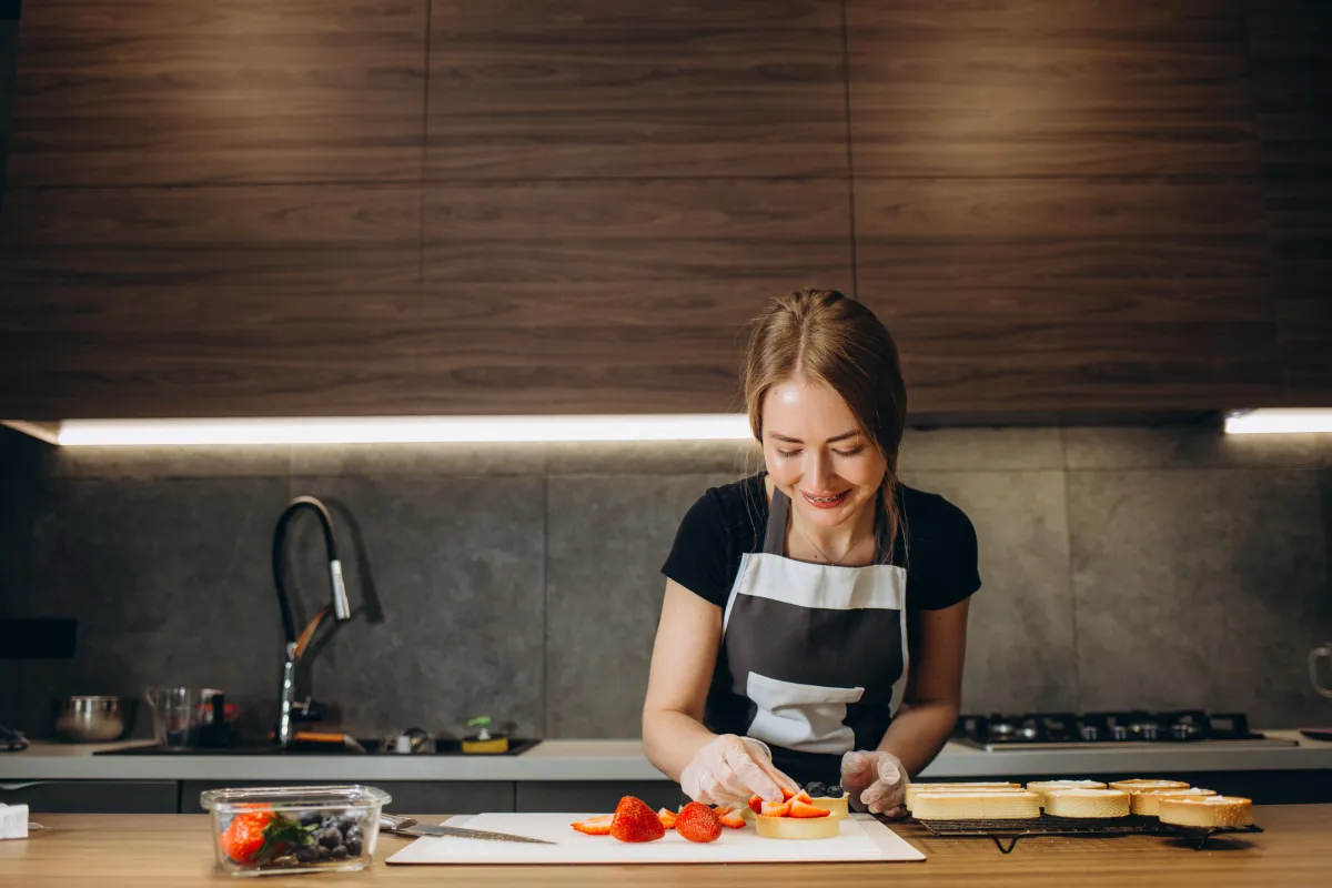 Femme qui coupe des fraises pour son cap patisserie