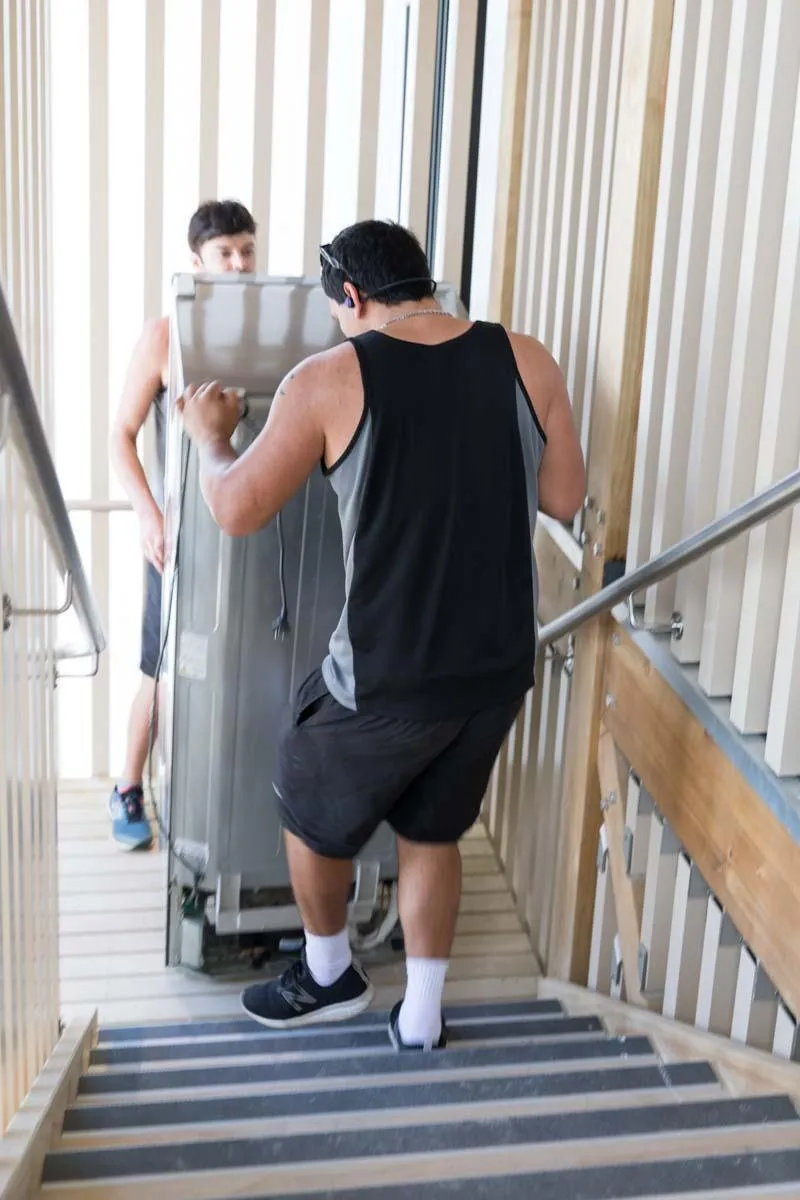 moving team moving a fridge down stairs