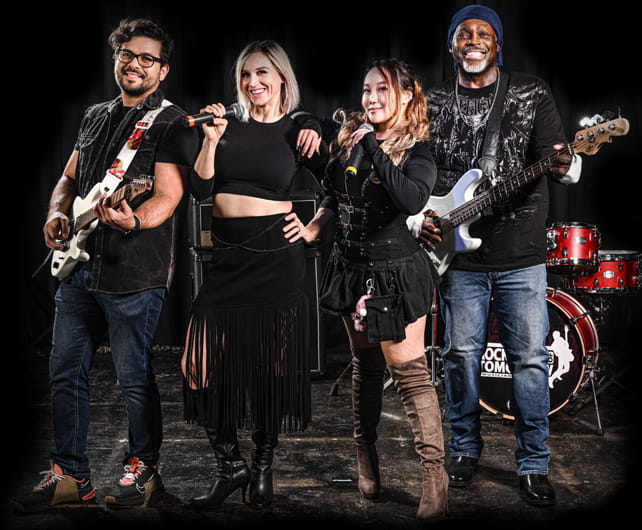Adults playing guitar, singing, and performing together in a band during a Rockstars of Tomorrow music lesson program.