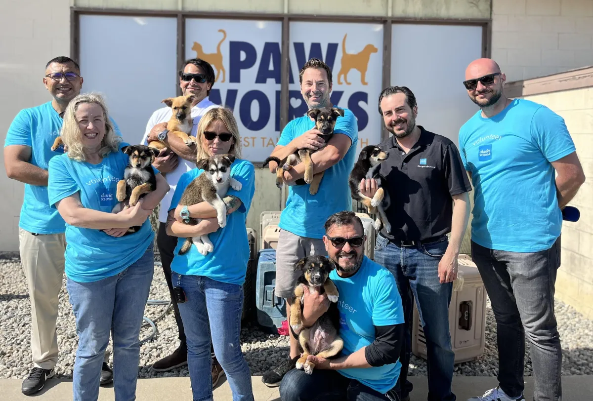 A group of volunteers with adoptable dogs in front of the Paw Works facility.