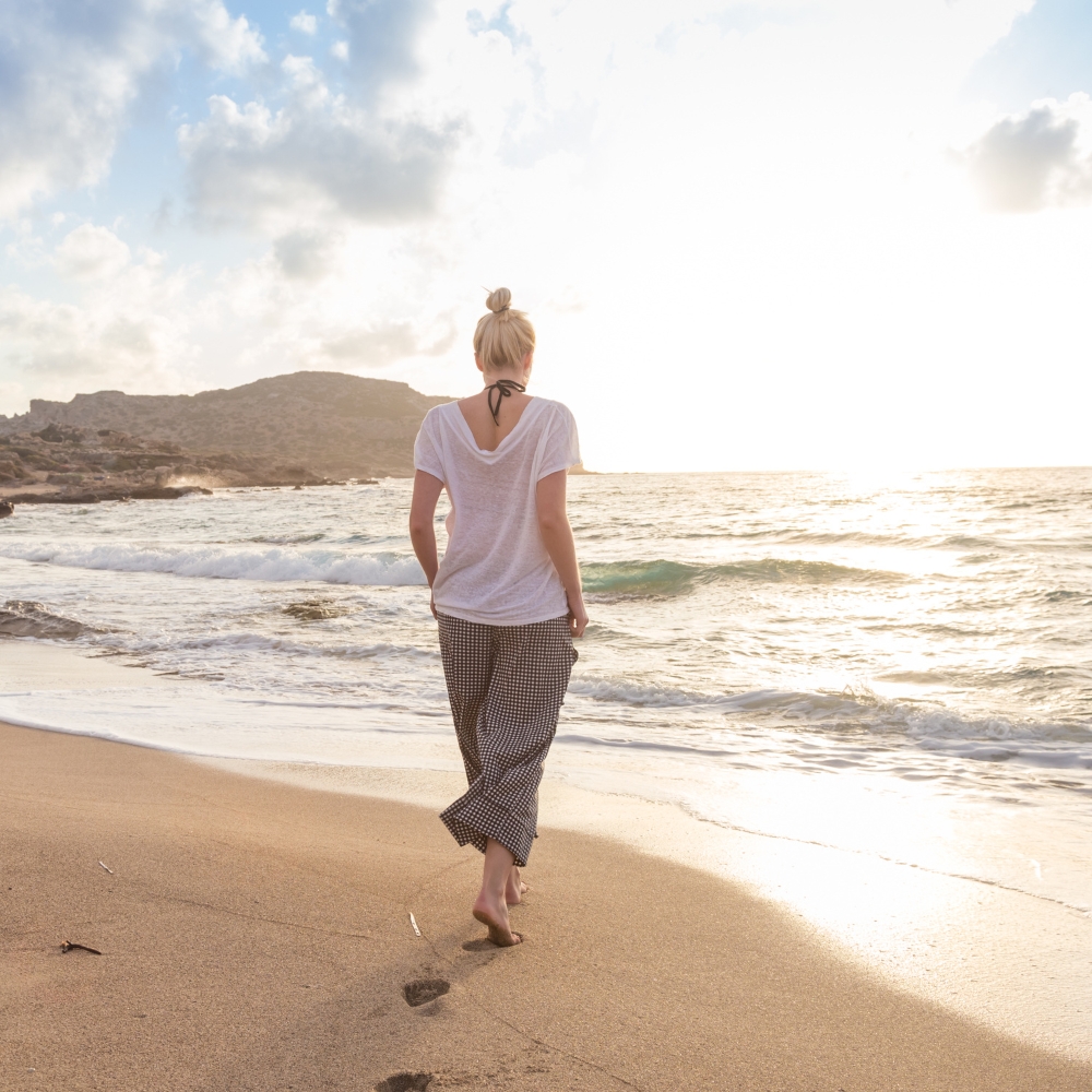 A woman walking on the beach deep in thought