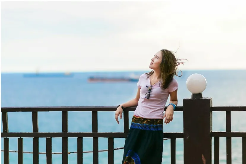 young woman looking up hopefully in front of boats