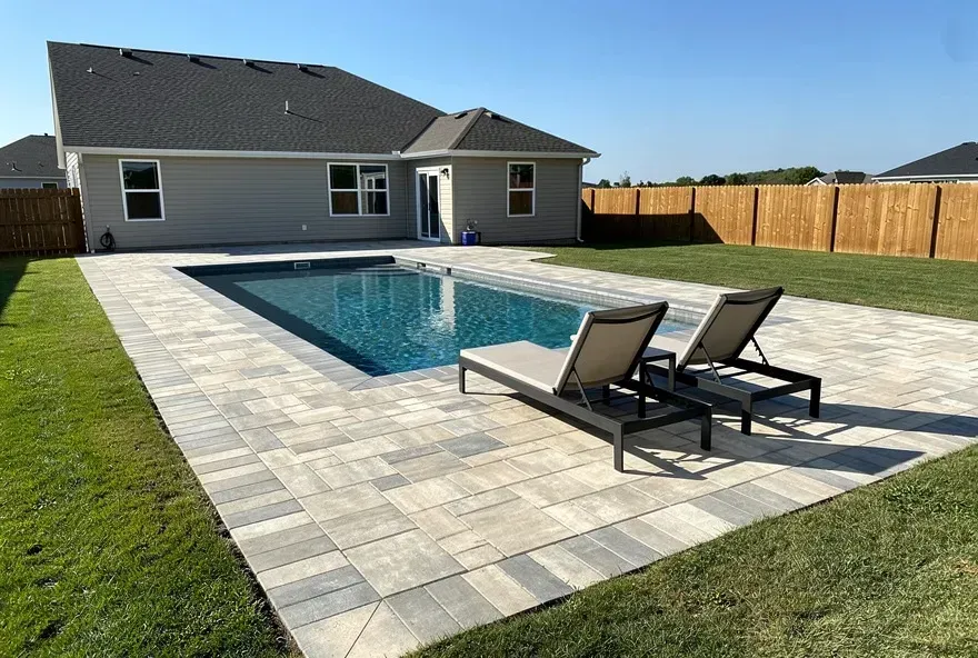 Light textured paver pool deck around an in-ground pool behind a Vineland home