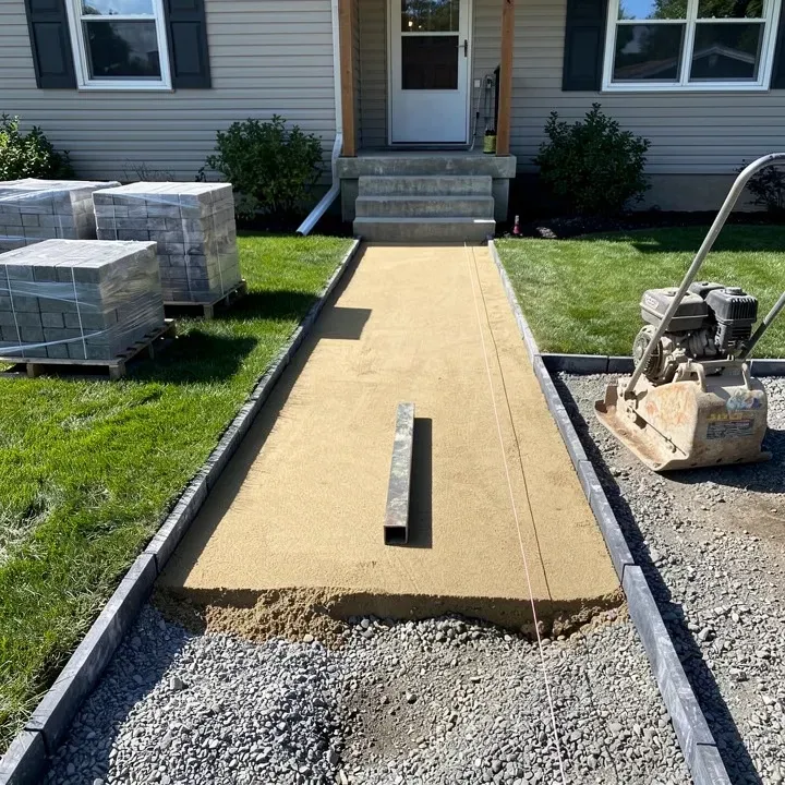 Prepared walkway with compacted gravel base and screeded sand before pavers are laid at a Vineland home