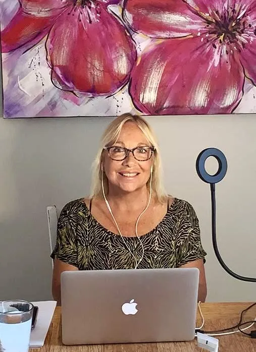 Anna peering over the computer with a smile on her face.