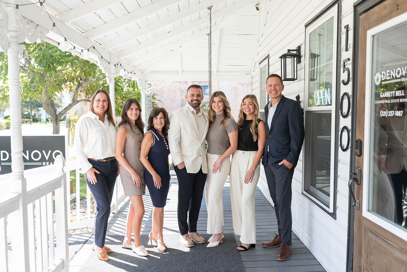 A diverse group of real estate professionals in business attire gathered around a glass table in a sunlit, modern office, discussing property portfolios with digital tablets and paperwork, conveying collaboration and opportunity.