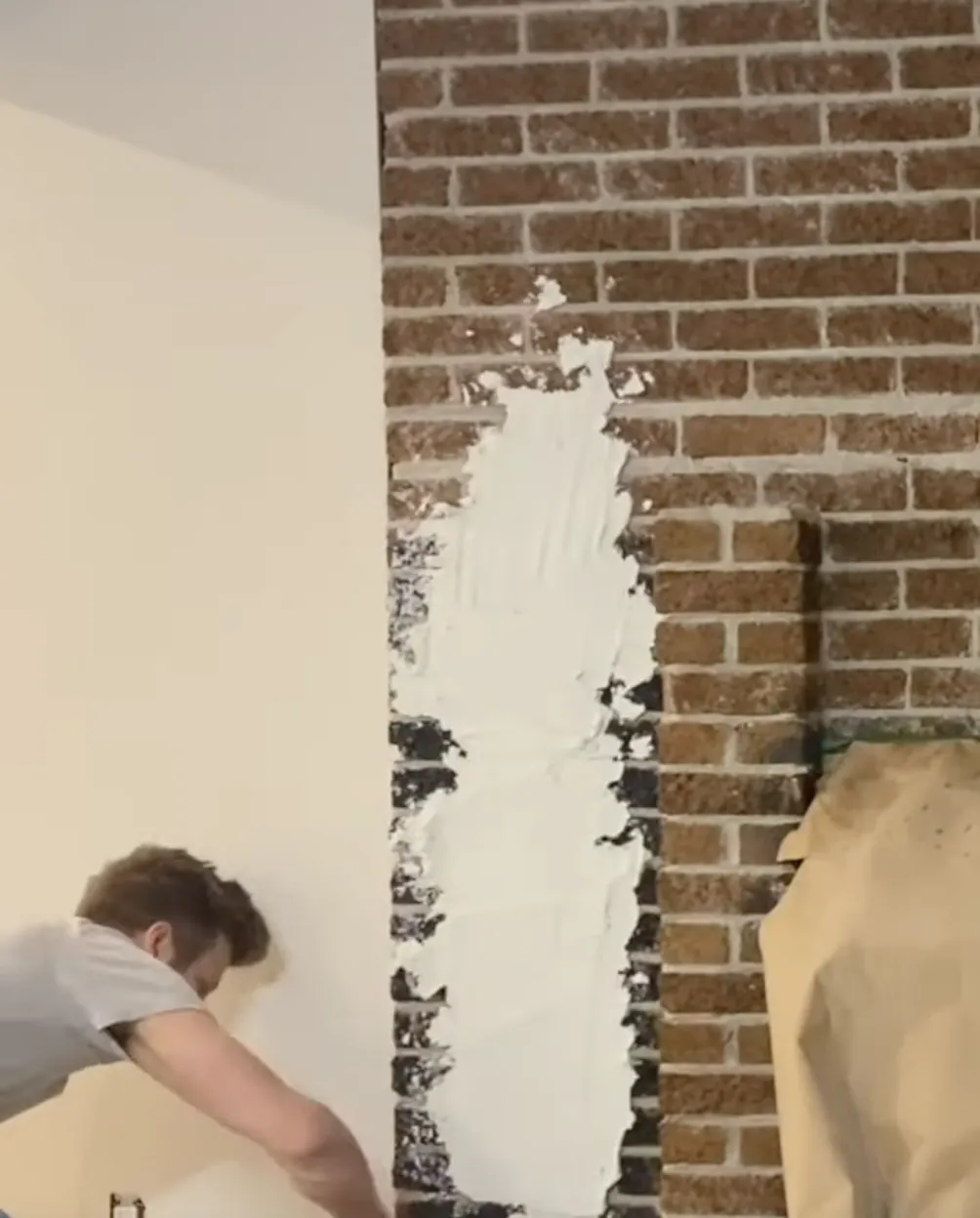 man applying stucco to brick fireplace