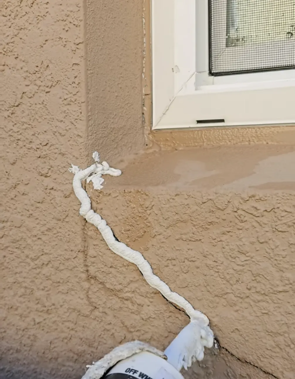 Stucco repair foam on cracked brown stucco 