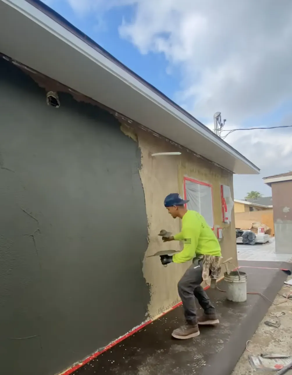 man applying new stucco to a commercial building