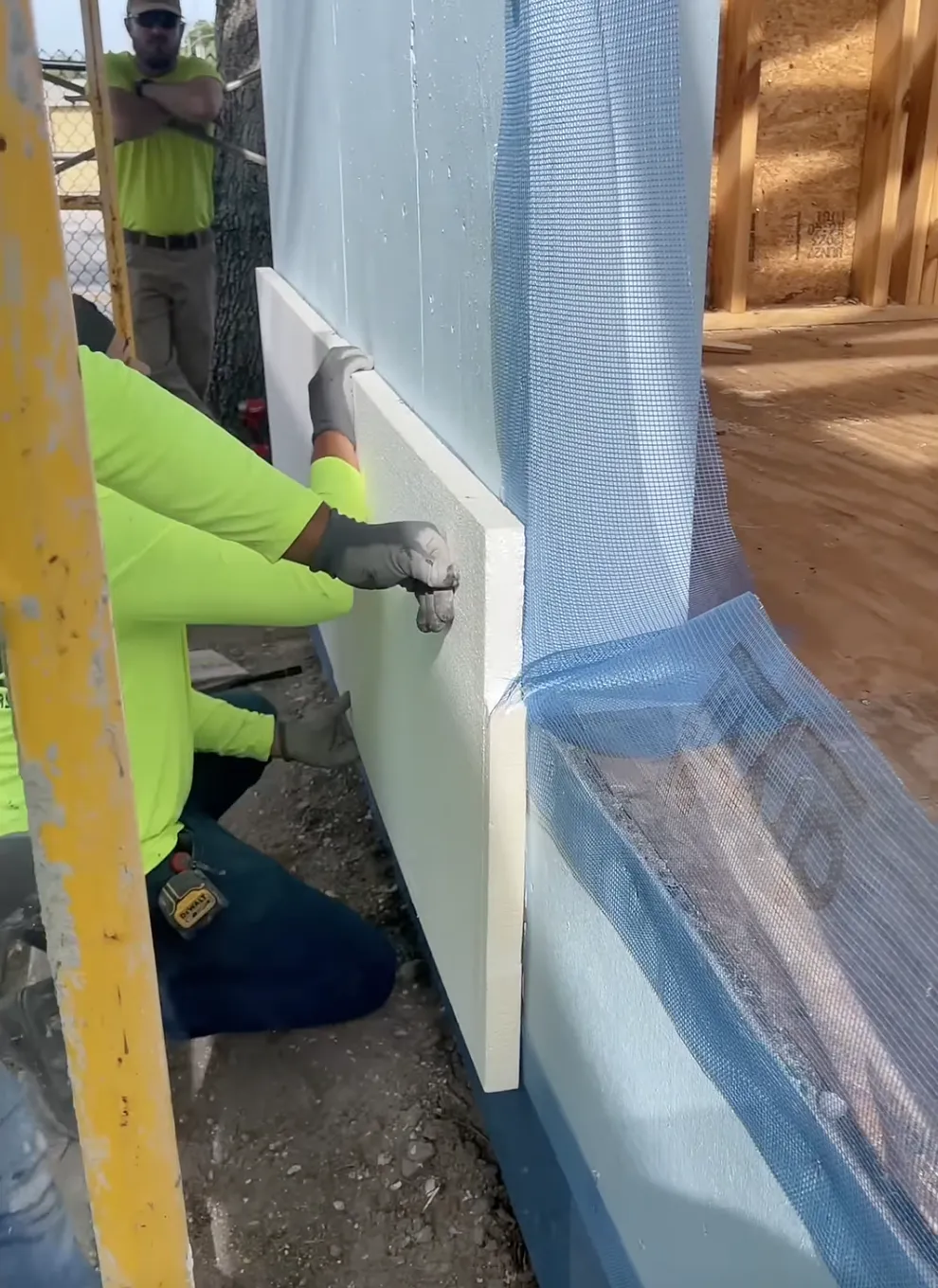 two men sticking an EIF's foam insert to a wall