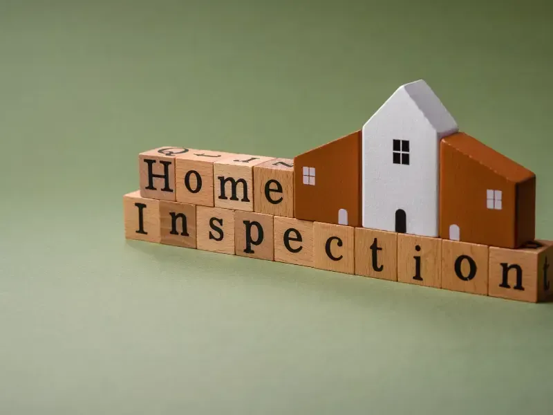 Wooden blocks spelling "Home Inspection" with miniature house model.