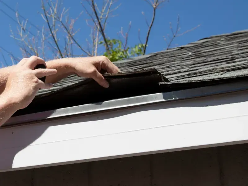 Inspector lifting shingle to check for roof damage.