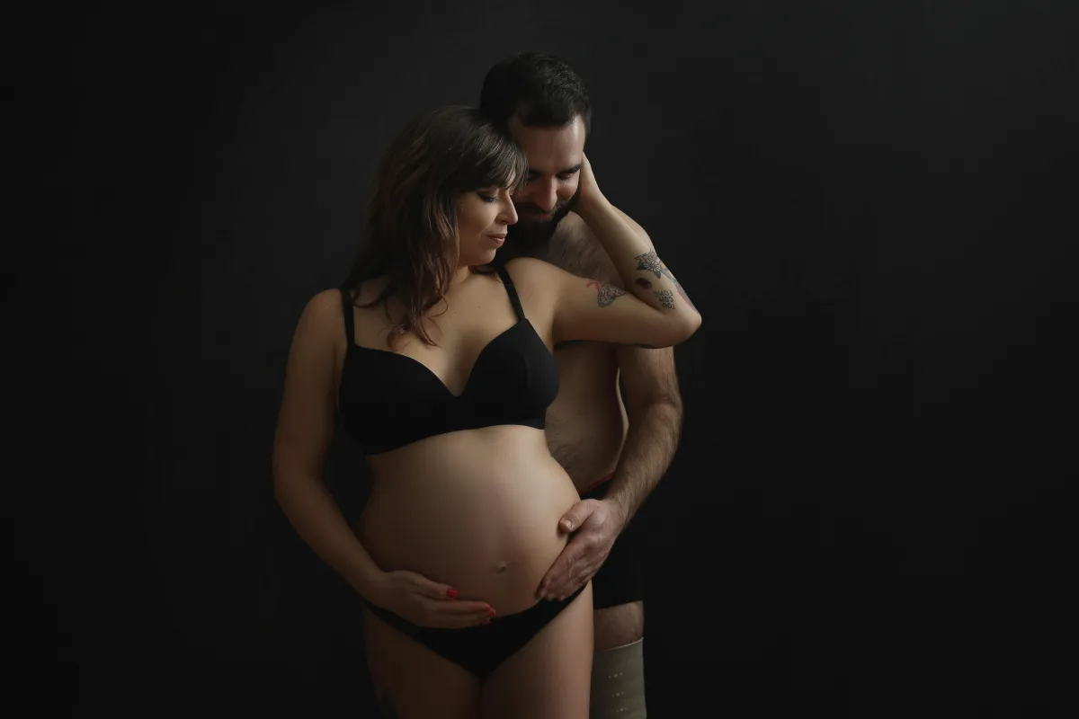 Husband and wife holding wife's bump - taken by professional photographer in Loughborough