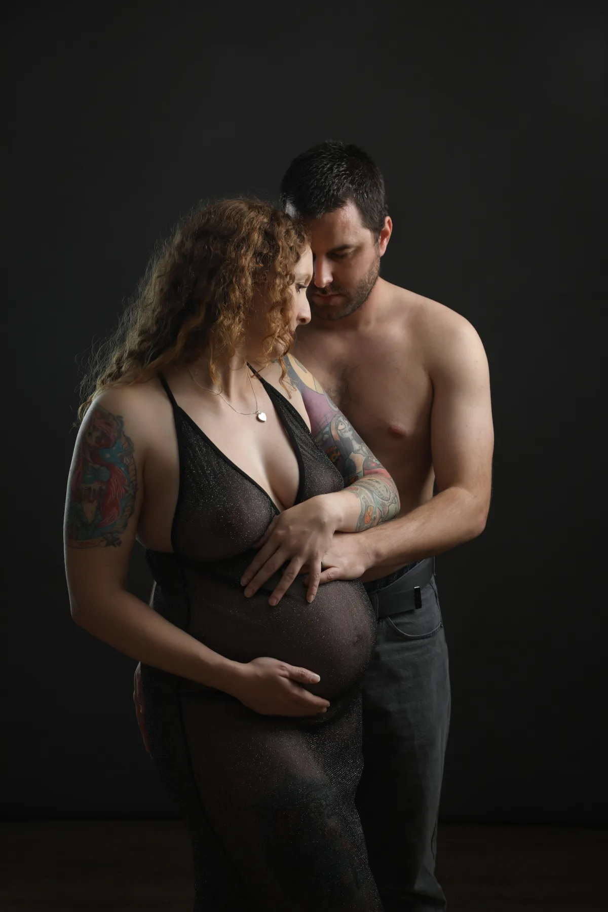 Husband and wife holding wife's bump - taken by professional photographer in Loughborough