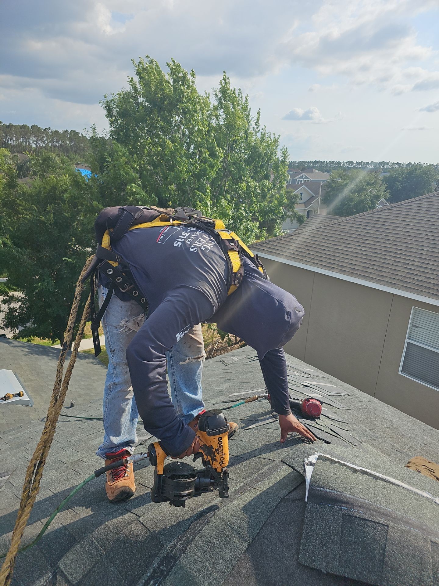 a man working on a roof with a power drill